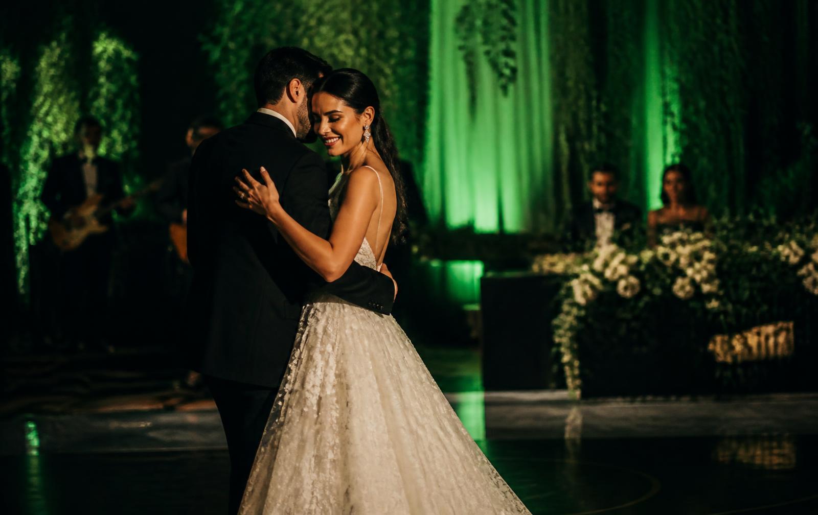 Couple sharing a first dance under emerald reception lighting